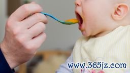 Father spoon feeding baby daughter - stock photo